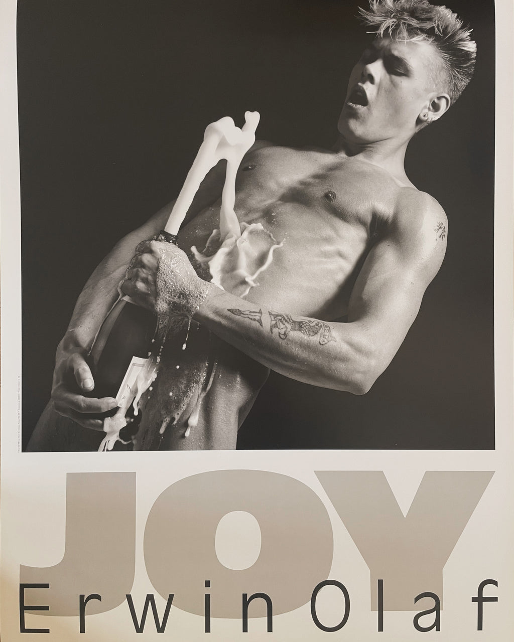 Erwin Olaf, Joy (Marc) (1985) poster: a black-and-white photograph of a bare-chested young man holding a bottle, with "JOY" and "Erwin Olaf" below.