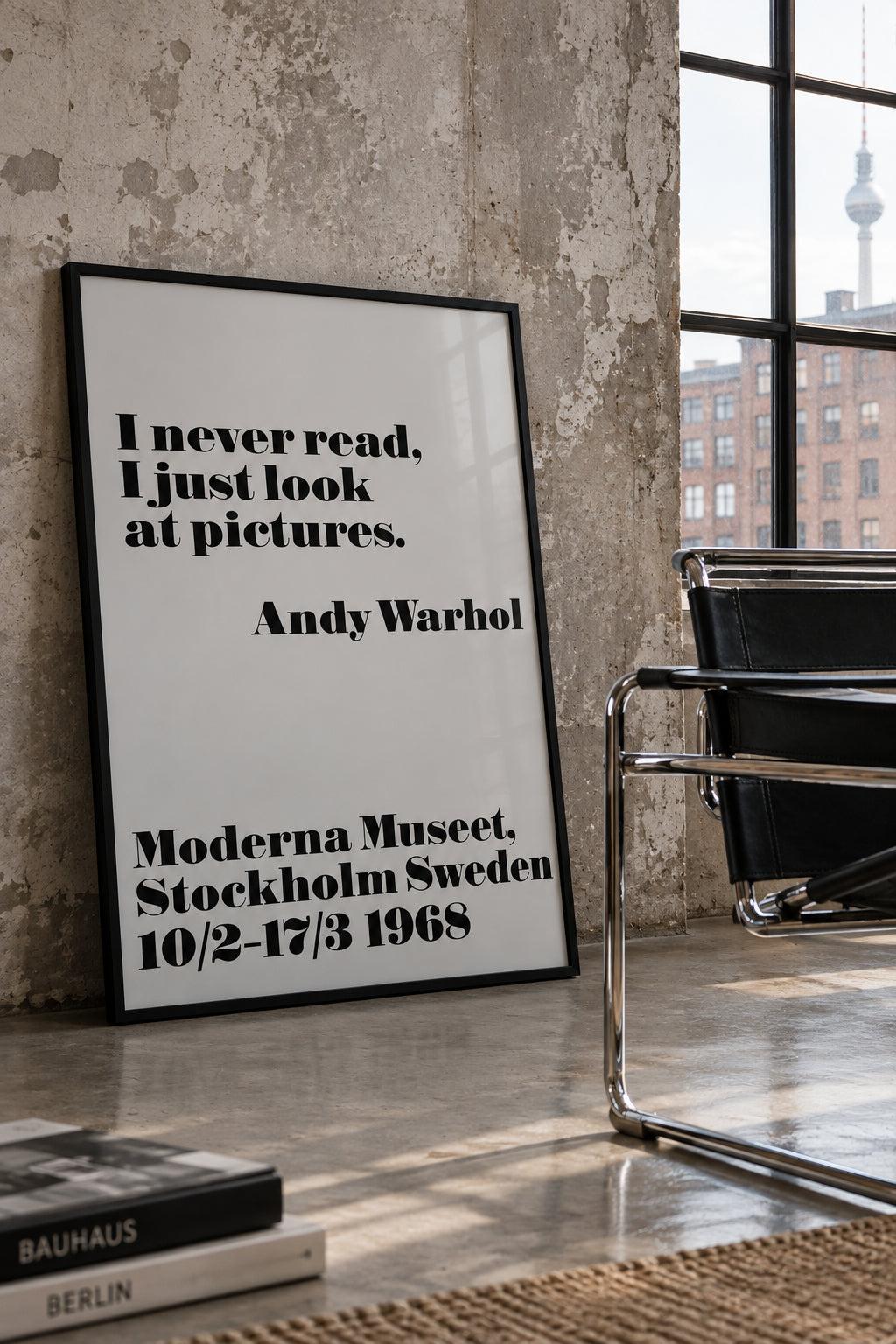 Andy Warhol, "I never read, I just look at pictures", Moderna Museet 1968 poster, shown framed, leaning against a concrete wall beside a tubular steel chair.